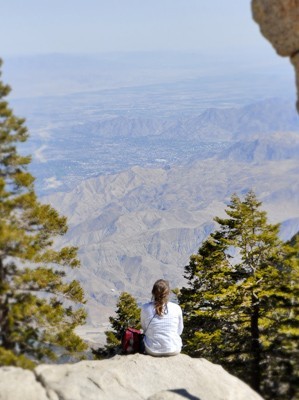 lady sitting on rock, looking over mountain range